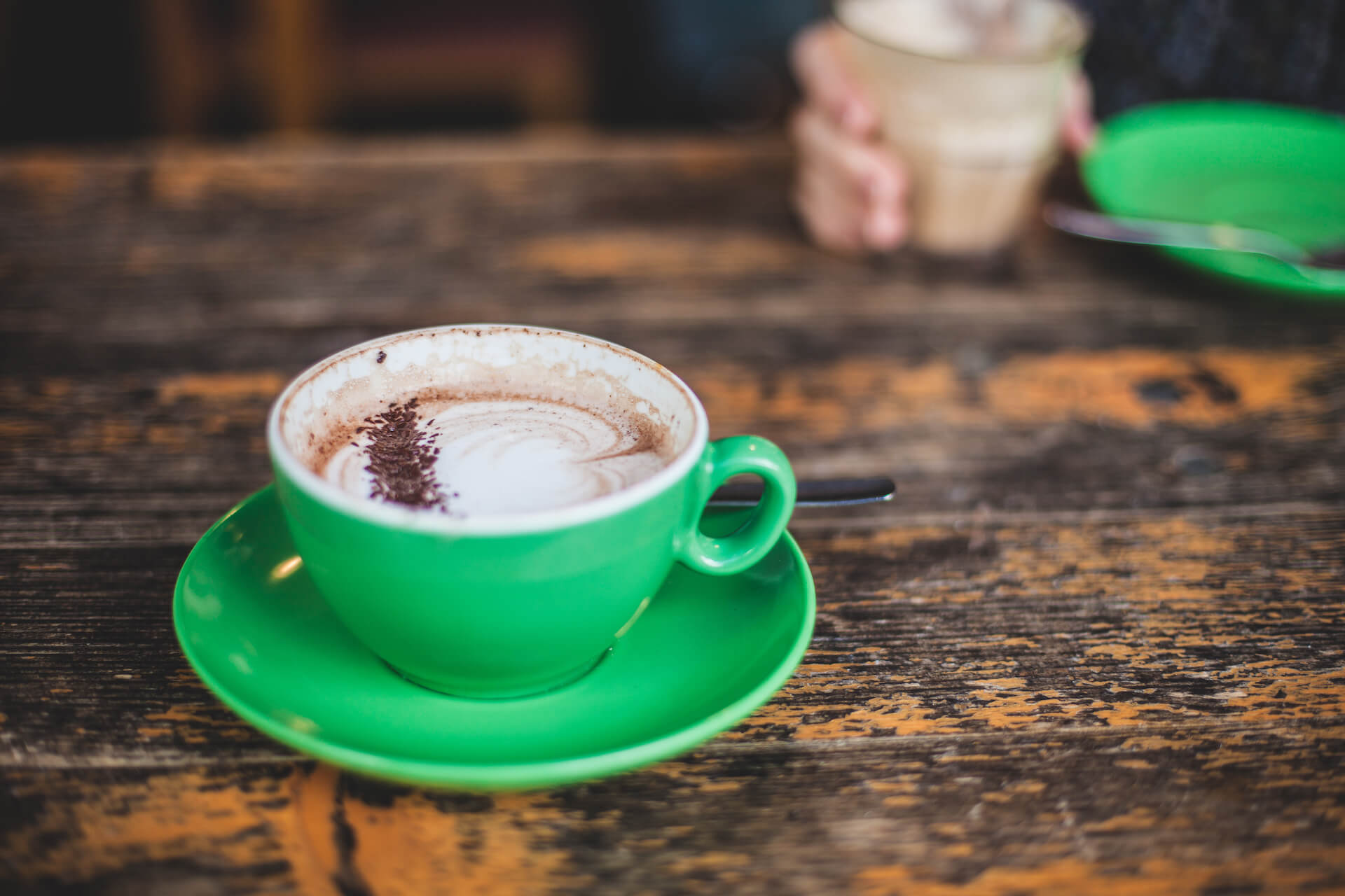 A green cup of a coffee on a wooden table